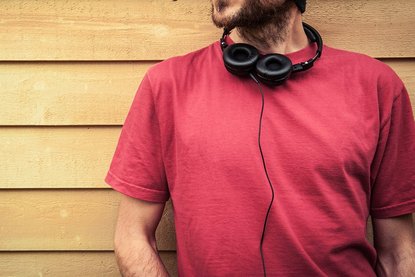 Mann im roten Shirt mit Kopfhörern um den Hals
